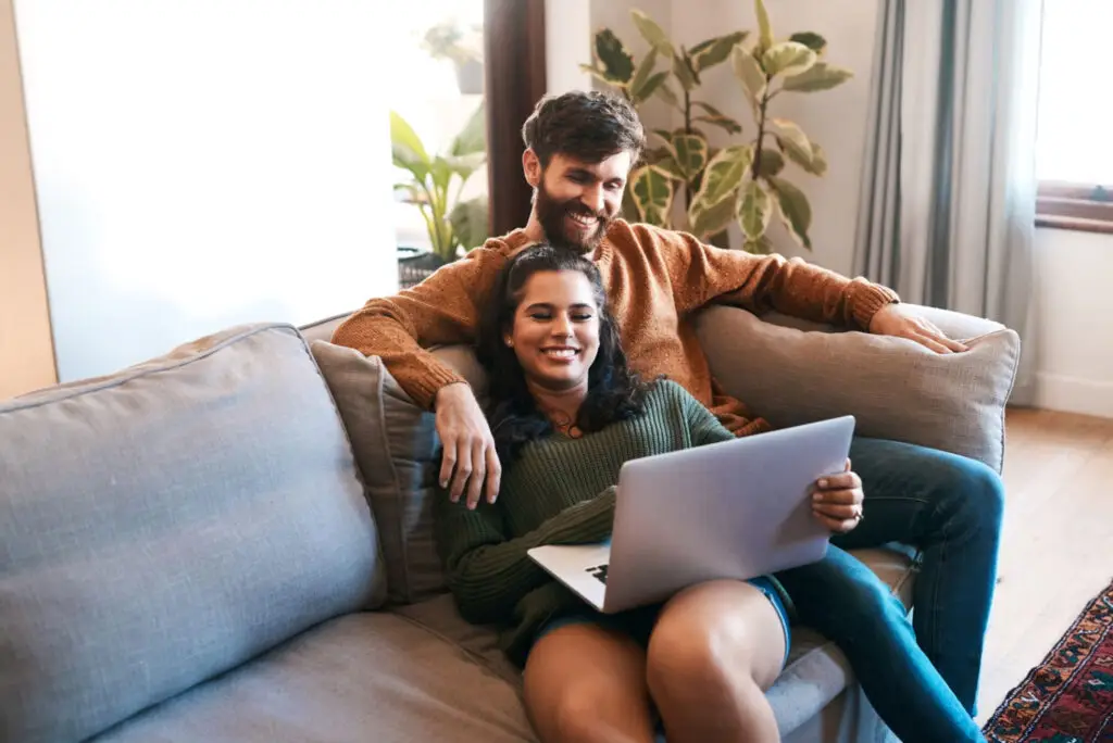 Shot Of A Young Couple Using A Laptop While Relaxing On The Sofa At Home