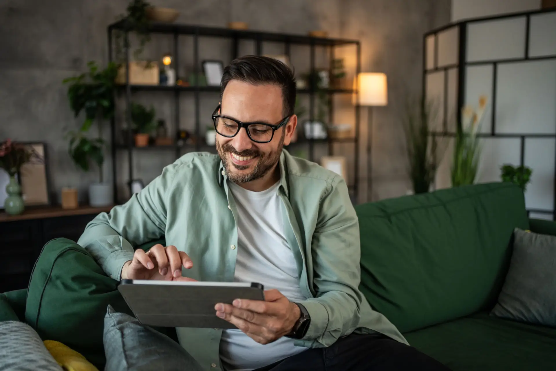 Shot Of A Happy Young Man Using His Tablet While Sitting On The Couch At Home